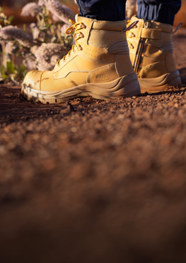 Tan boots on a dirt path with a blurred natural background